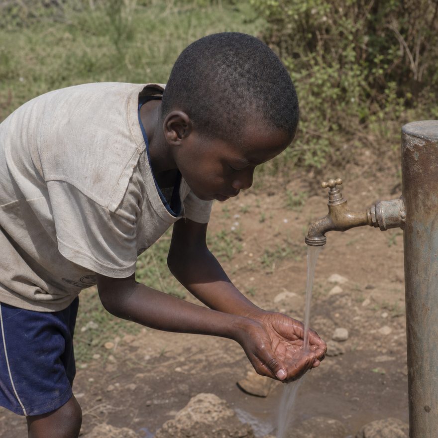 Boy drinking clean water from a village standpipe
